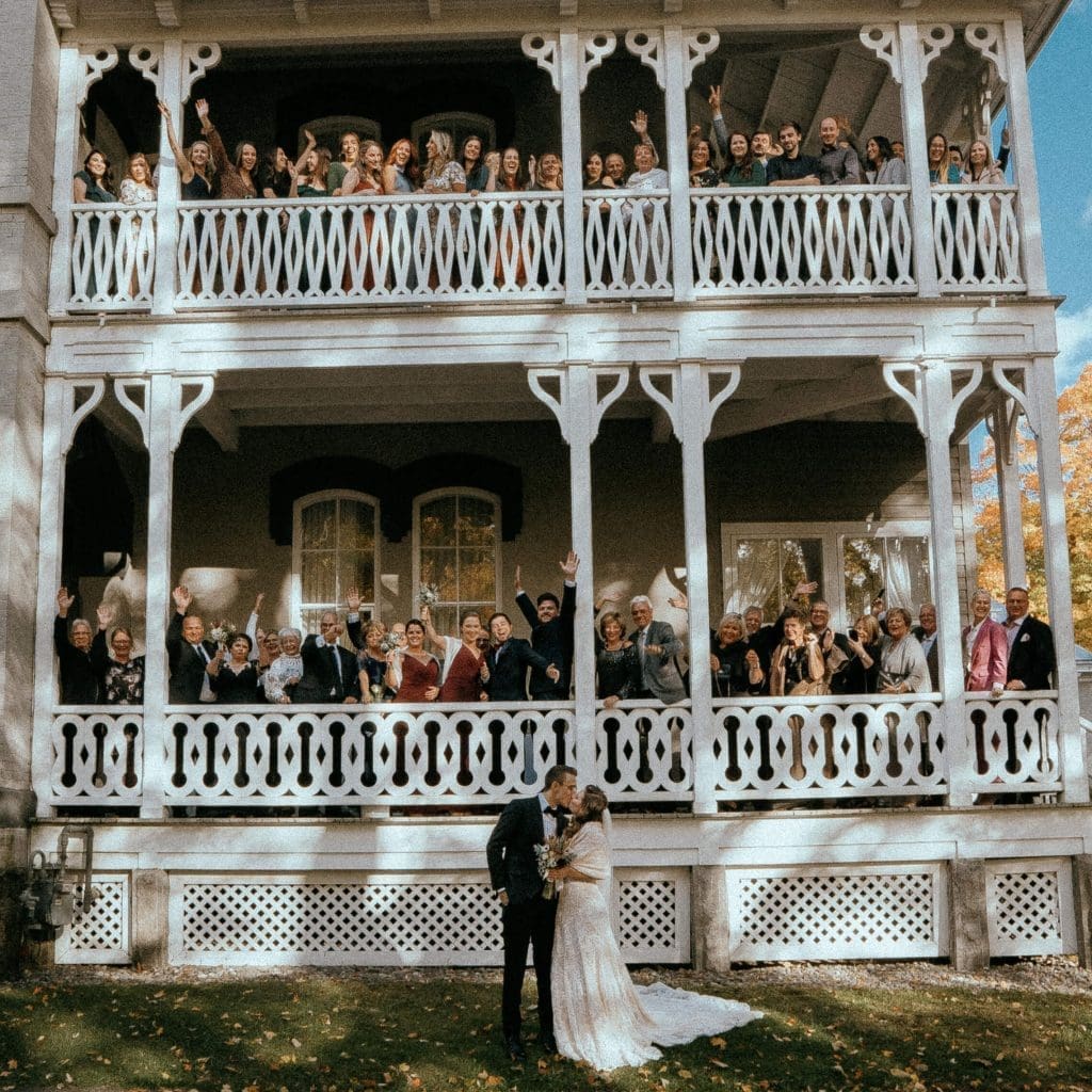 Groupe d'invités sur deux étages, au mariage de nouveaux mariés qui s'embrassent