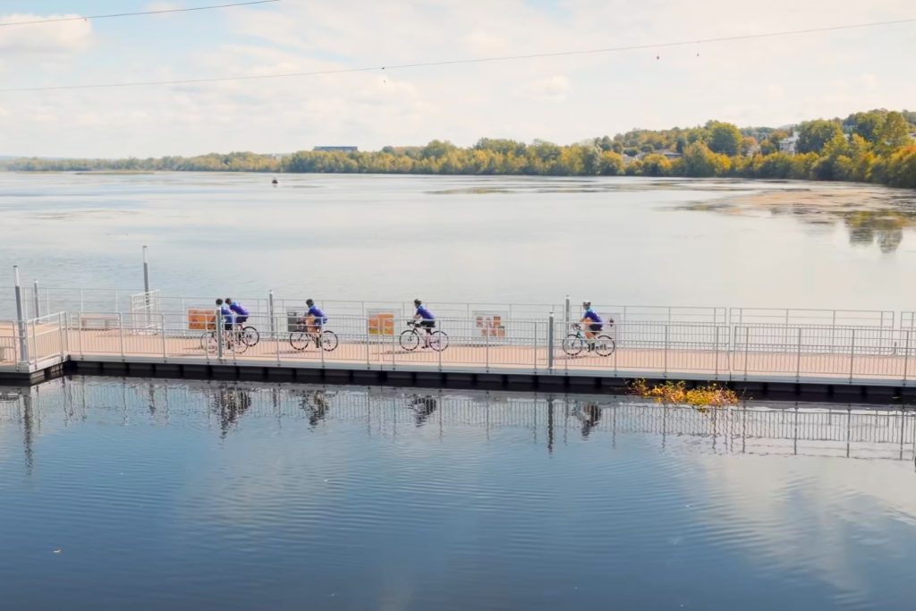 Cyclistes de l’équipe DSMA traversant une passerelle au-dessus du lac lors de l’événement Vélo DSMA, symbole de cohésion et d’engagement envers la Fondation du CHUM.