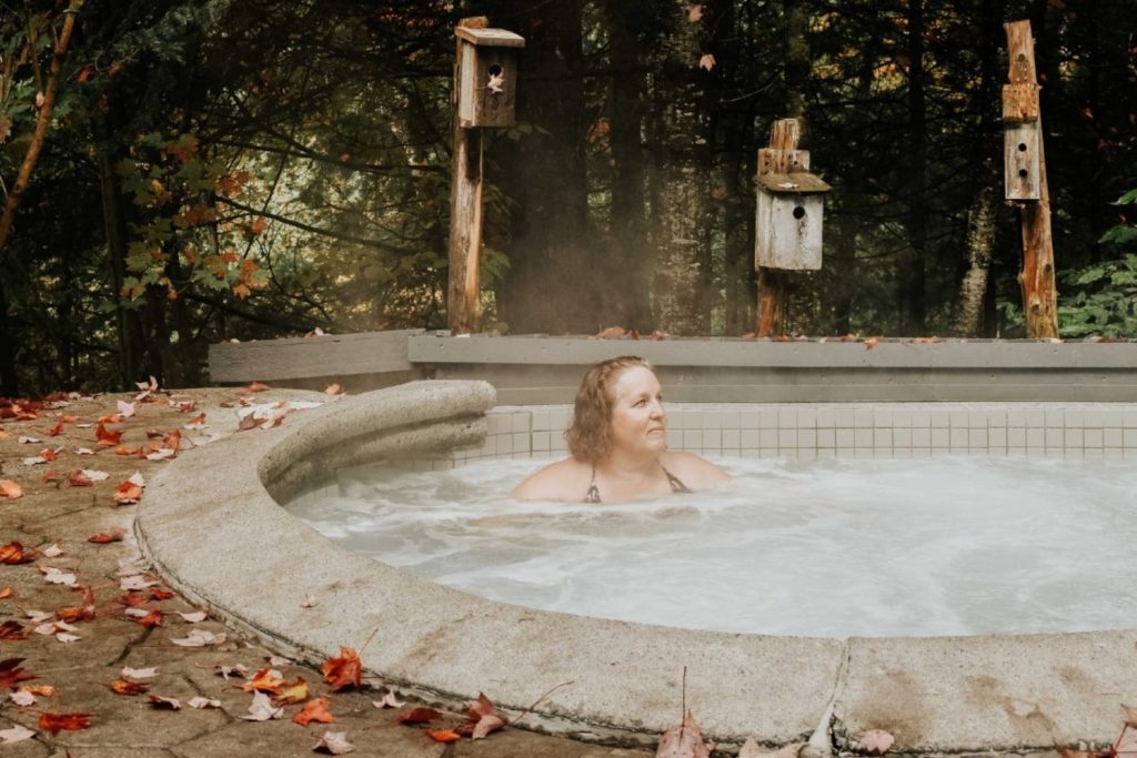 Invitée profitant d’un bain chaud extérieur dans un spa nordique entouré de nature près du Manoir Davis, symbole de relaxation et de ressourcement après une retraite corporative